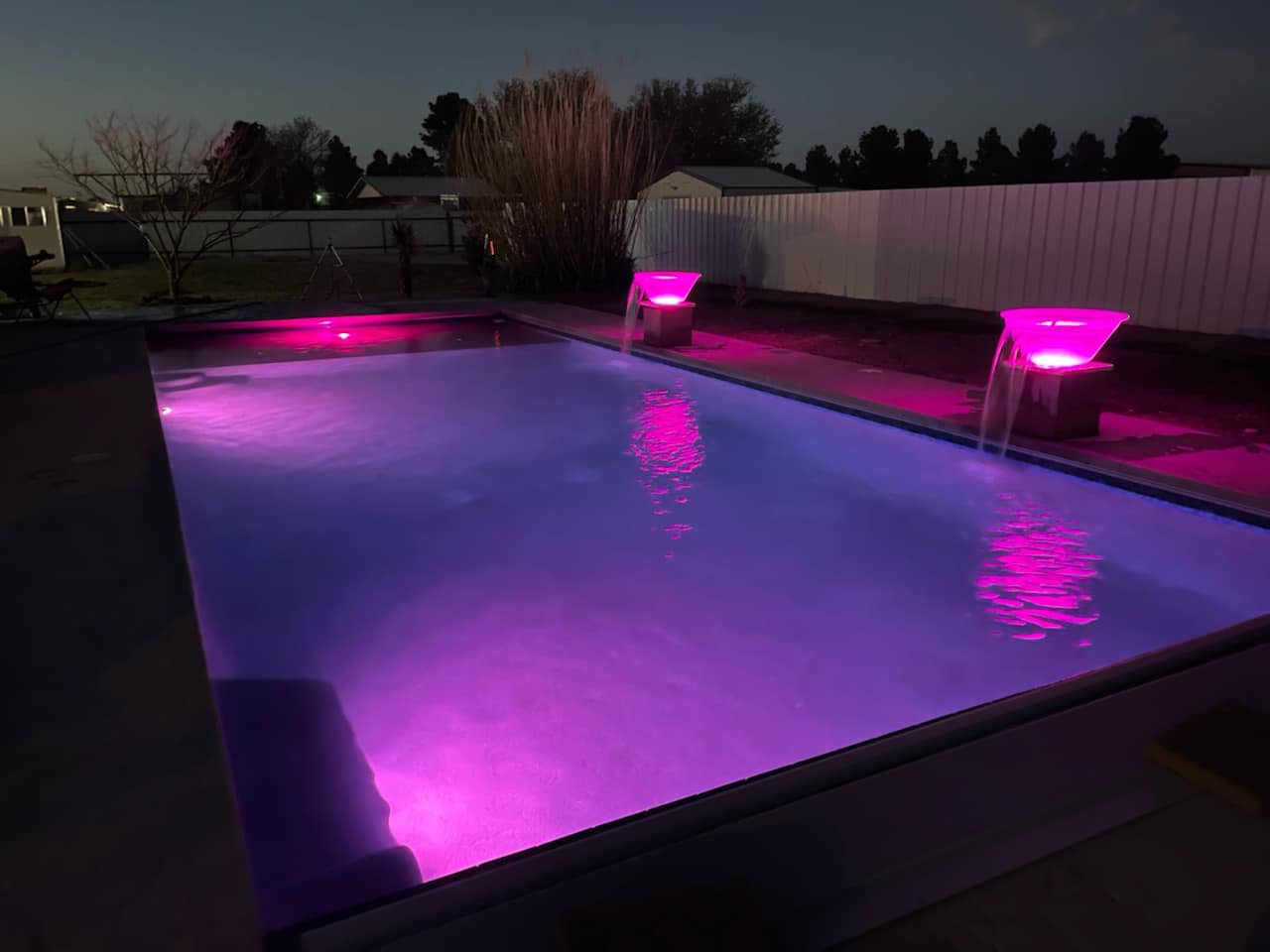 Geometric rectangular pool with illuminated water bowls and purple LED lighting.