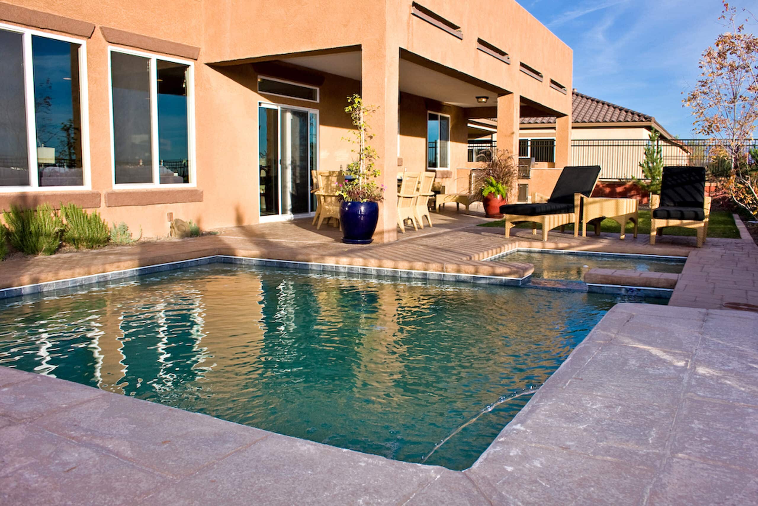Geometric gunite pool with a raised spa and stamped concrete decking in a Rio Rancho backyard.