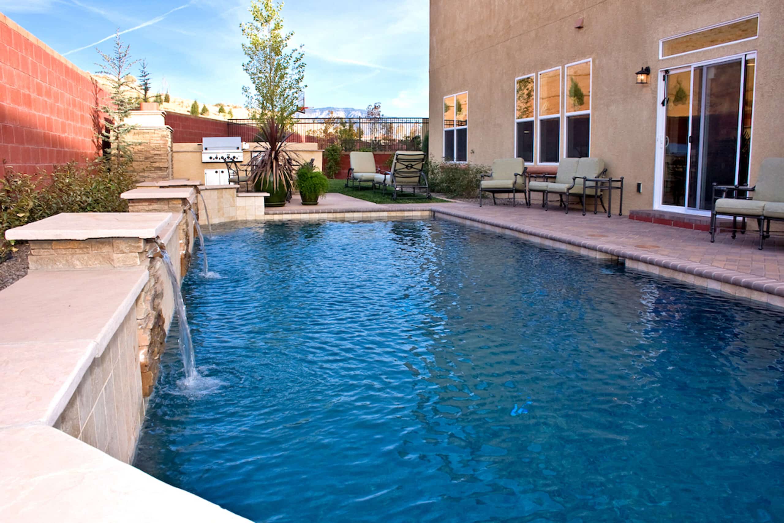 Custom rectangular pool in the Cabezon neighborhood featuring a raised wall with sheer descent waterfalls.